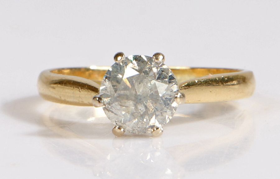 An 18 carat gold and diamond solitaire ring, the heads set with a claw mounted brilliant cut diamond