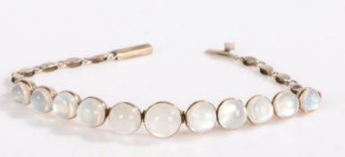 A yellow metal bracelet set with eleven moonstone cabochons in a graduating order, approximately
