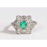 Platinum emerald and diamond cluster ring, possibly Edwardian. The central emerald is framed by