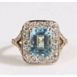 A 18 carat gold diamond and aquamarine ring, the head set with a baguette cut aquamarine stone