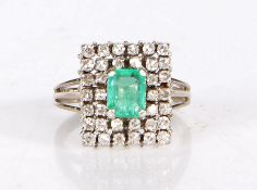 An 18 carat white gold emerald and diamond ring, having an emerald to the centre, set on a raised