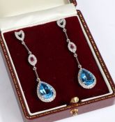 A pair of diamond pink topaz and blue topaz earrings, set with a claw mounted tear drop blue topaz