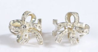 A pair of 18 carat white gold and diamond earrings in the form of bow, decorated with a central