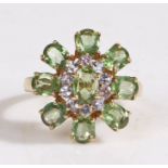 A 9 carat gold peridot ring, the head in the for of a flower nine peridots and ten stones, ring size