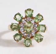 A 9 carat gold peridot ring, the head in the for of a flower nine peridots and ten stones, ring size