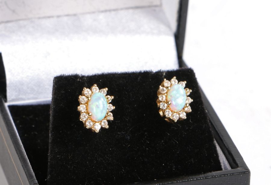A pair of 9 carat gold opal and white sapphire earrings, the head set with a claw mounted oval cut