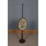 Edwardian mahogany and needlework fire screen, the oval needlework screen depicting flowers together