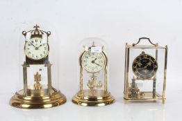 Two anniversary clocks, each under glass domes and one other brass and glass clock (3)