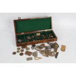 Collection of various metal buckles and tokens housed within a wooden box (Qty)