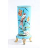 Late Victorian blue pressed glass vase, over painted with a perched bird and foliage, raised on four