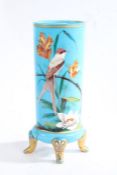 Late Victorian blue pressed glass vase, over painted with a perched bird and foliage, raised on four