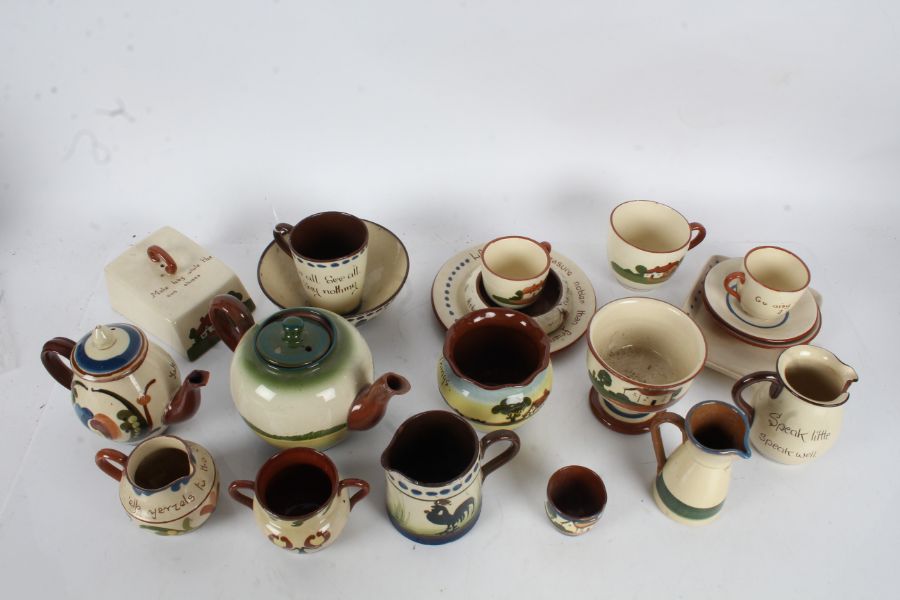 Collection of Torquay pottery 'Motto' ware, to include butter dish, cups and saucers, teapot, plates