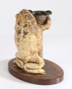 Taxidermy novelty smoking companion stand, modelled as a toad holding aloft an ashtray with two