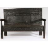 18th Century and later oak settle, the foliate carved panel back flanked by two mask carved