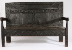 18th Century and later oak settle, the foliate carved panel back flanked by two mask carved