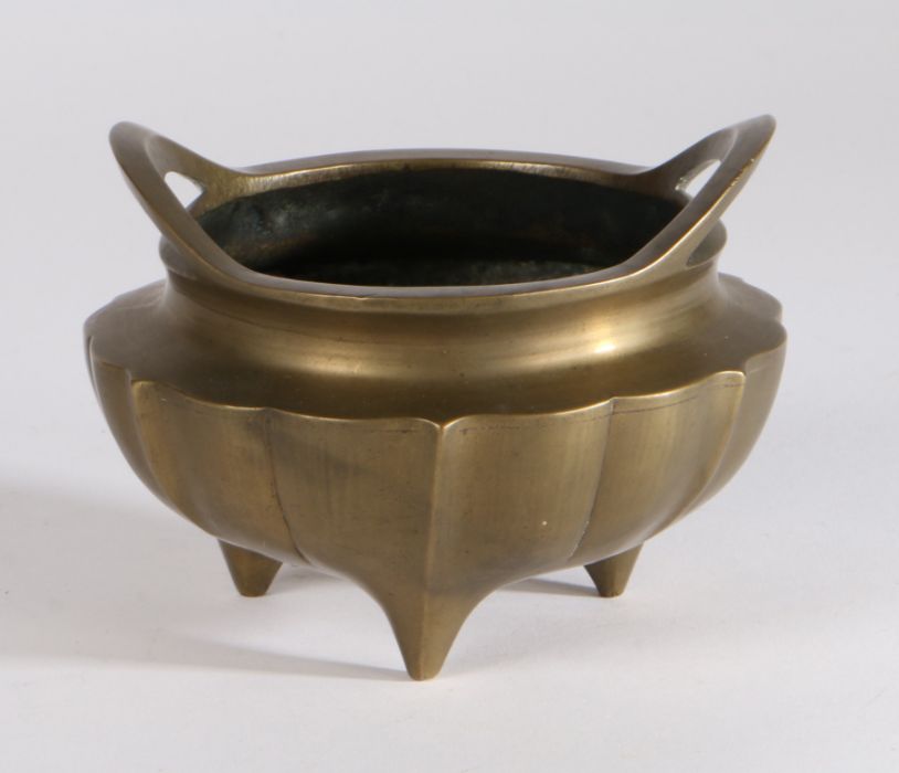 Chinese bronze ding censer, the shaped body with open loop handles, raised on three tapering feet,