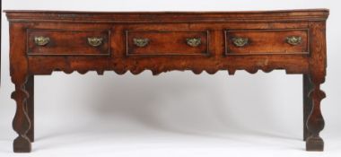 A George I oak and elm low dresser, circa 1720 Having a boarded top with applied moulded under-edge,