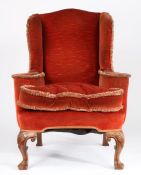 George II style wingback armchair, the red upholstery with tasselled edging, with loose seat