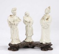 Three Chinese blanc de chine figures, modelled as ladies holding fans, on a pierced carved