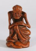 Chinese bamboo carving depicting an emaciated male figure seated on a naturalistic base, 17cm high