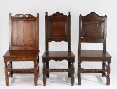 Three George III and later oak dining chairs, all with panelled backs and solid seats, raised on
