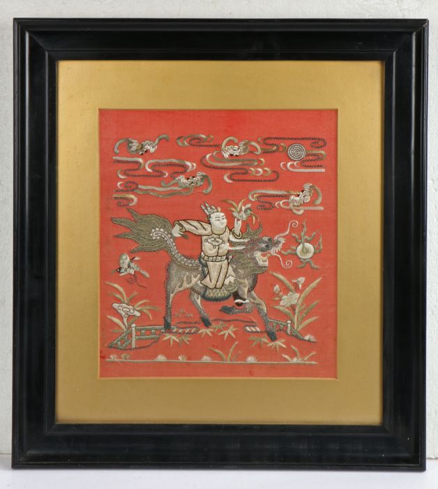 Chinese red silk panel, embroidered in silver thread with central depiction of an immortal on