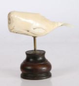 19th Century marine ivory sperm whale, on a brass stem and turned wooden base, 16cm high, 16.5cm