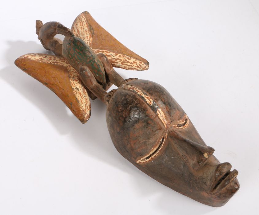 Ivory Coast Senufo Kpelie mask, surmounted by a bird with spread wings, with traces of paint, 58cm