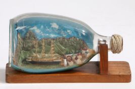 Ship in a bottle, depicting a three masted ship moored in a harbour with volcano and hills to the