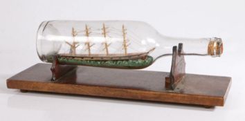 Early 20th Century ship in a bottle, the four masted ship on choppy seas, on a mahogany stand, 35.