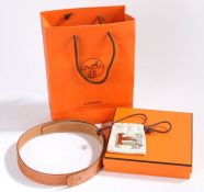 A Hermes tan leather Constance belt with panished silvered H buckle in cloth bag, belt 100cm length,