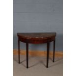 George III mahogany demi lune card table, the top decorated with cross banding, raised on tapering