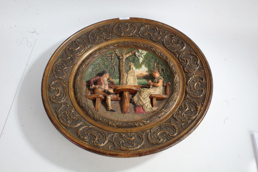 Large 20th wall plaque, with a circular rim decorated with scroll decoration and a scene of a man
