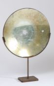 20th Century parabolic mirror, of typical form, raised on a later iron frame, 45cm wide, 67cm high