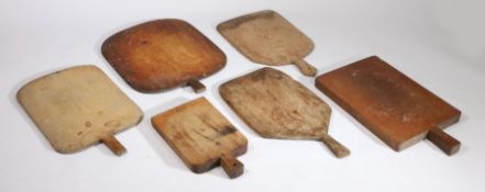 Six rustic chopping boards, the majority with tapering handles above rectangular and shaped