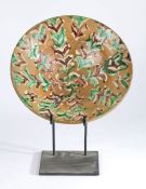 19th Century slipware charger or bowl, in browns, creams and green, restored, 29.5cm wide