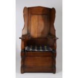 Oak lambing chair, the arched high back above a seat flanked by panelled enclosed arms and turned