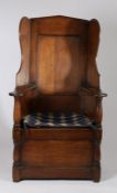 Oak lambing chair, the arched high back above a seat flanked by panelled enclosed arms and turned