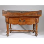 French butchers block on stand, the shaped top above a frieze drawer with shaped apron, raised on