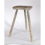 Primitive 20th Century stool, with a trapezium shaped seat above three chamfered legs, with remnants