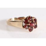 9 carat gold and garnet ring, the head in the form of a flower set with seven claw mounted round cut