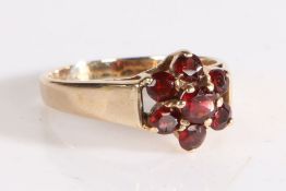 9 carat gold and garnet ring, the head in the form of a flower set with seven claw mounted round cut