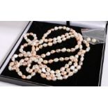 An elegant long multi-layer pearl necklace and pearl earrings, the necklace comprised of alternating