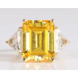 14 carat gold ring having a large emerald cut yellow stone to the centre with trillion cut white