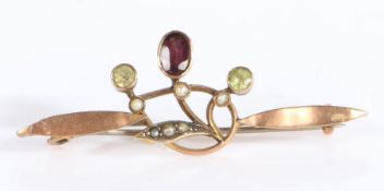Unmarked gold coloured metal brooch, the central amethyst flanked by two peridot suspended from a