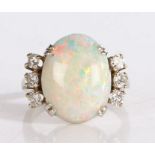 Opal and diamond ring, the central oval opal flanked by three diamonds to each shoulder, on a
