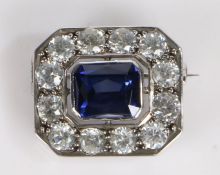 A decorative brooch, the central blue paste within a pierced mount and clear paste set border with