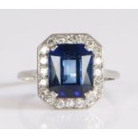 Platinum sapphire and diamond ring, the claw set emerald cut sapphire mounted on an elongated