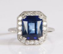 Platinum sapphire and diamond ring, the claw set emerald cut sapphire mounted on an elongated