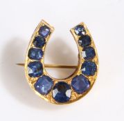 Sapphire set horseshoe brooch, with a row of eleven sapphire to the yellow metal mount,4.2 grams,